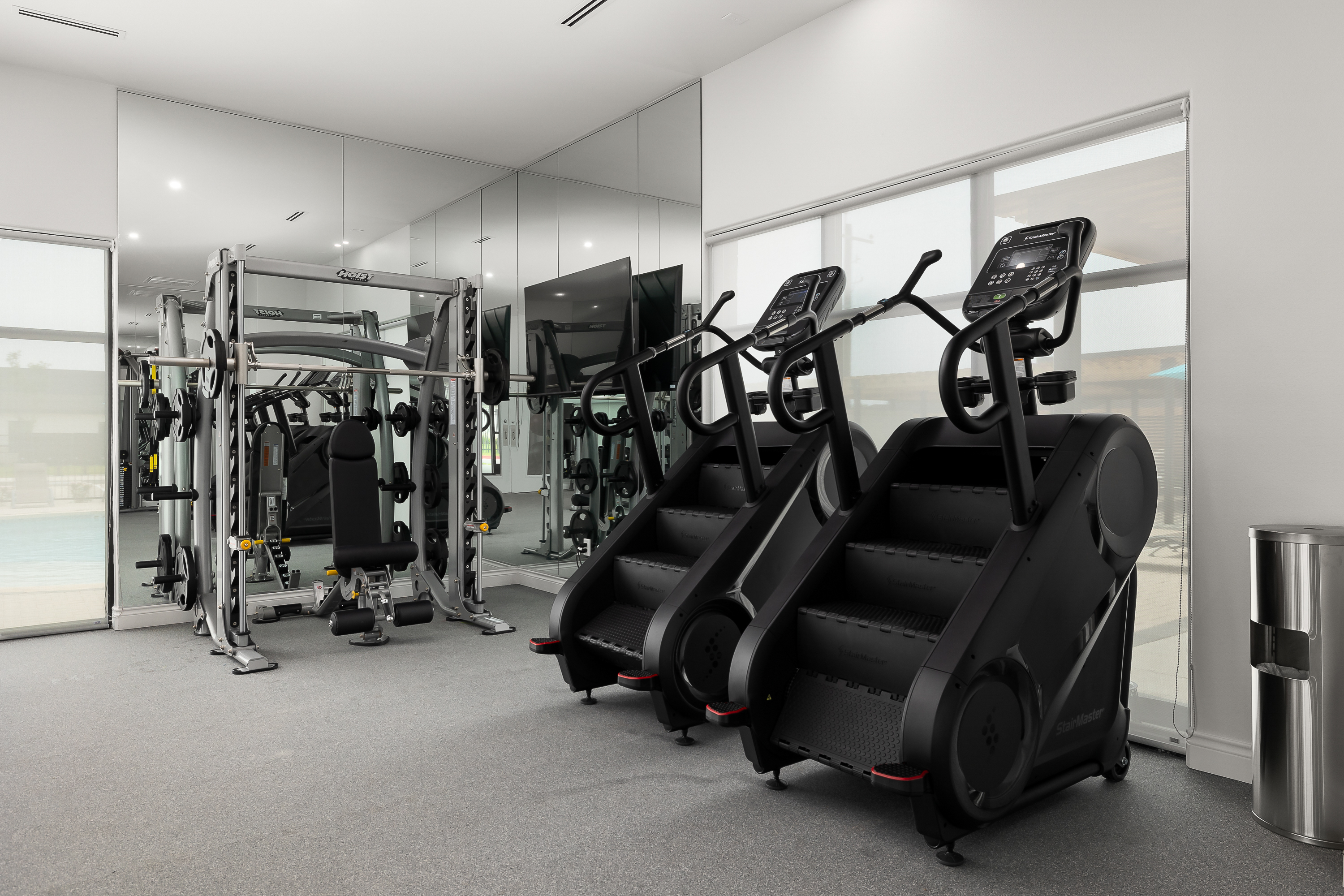 Gym interior with a row of treadmills against a mirrored wall and weight machines visible in the background.