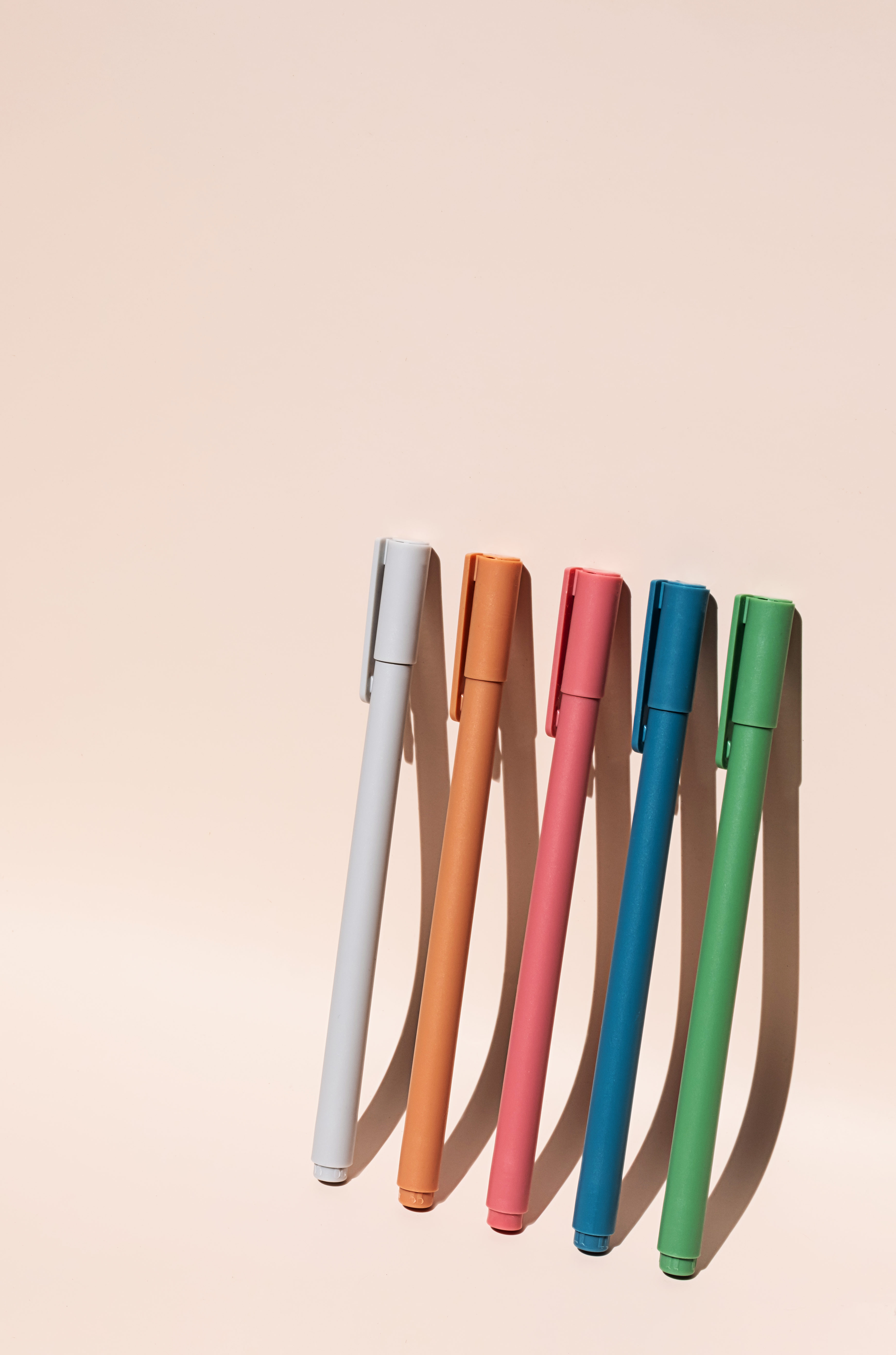 Colorful marker pens angled along the bottom edge on a pale peach background.