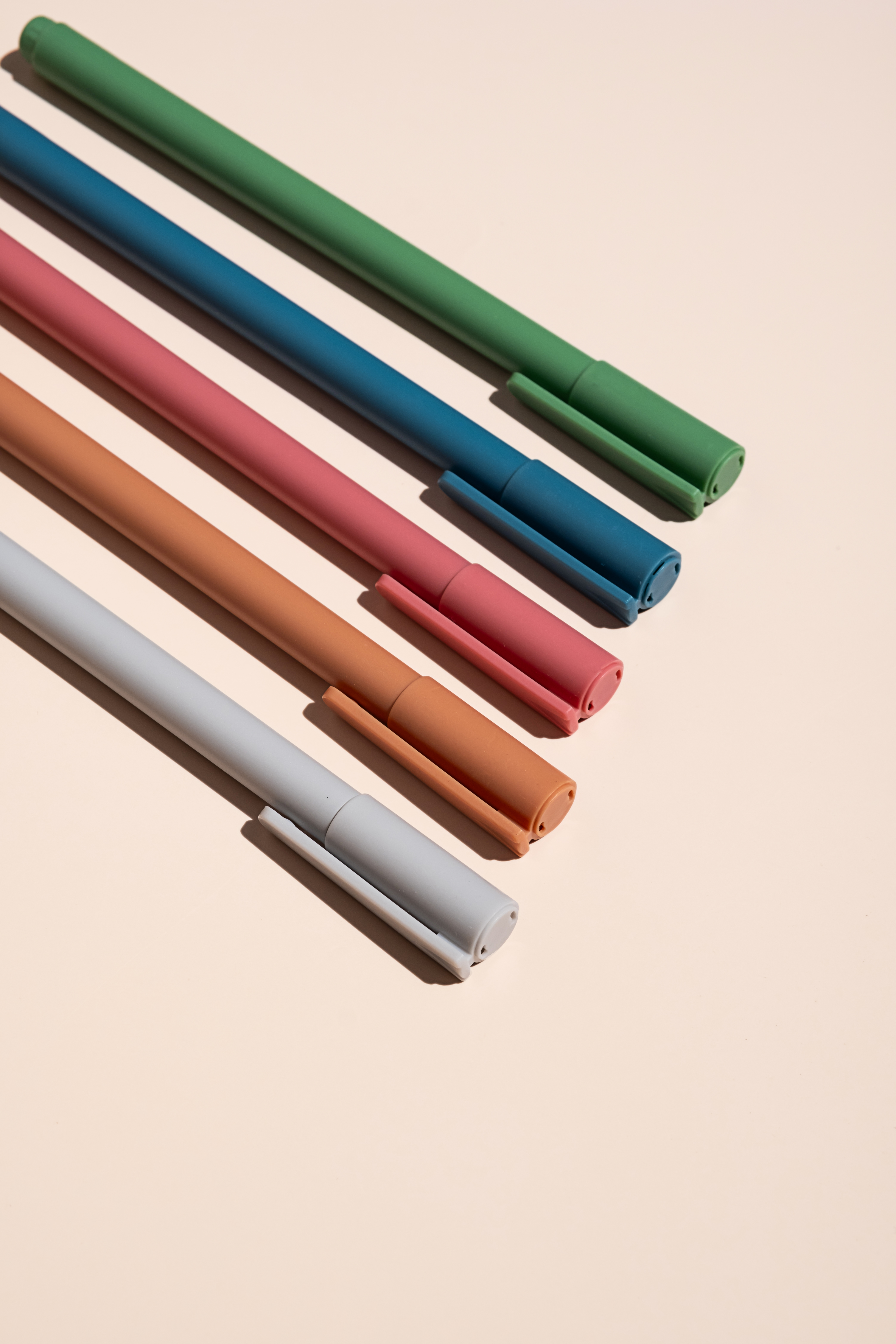Set of pastel-colored marker pens arranged diagonally on a pale surface