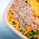 Close-up of a colorful salad with sunflower seeds, corn, avocado, shredded carrots and greens in a bowl?