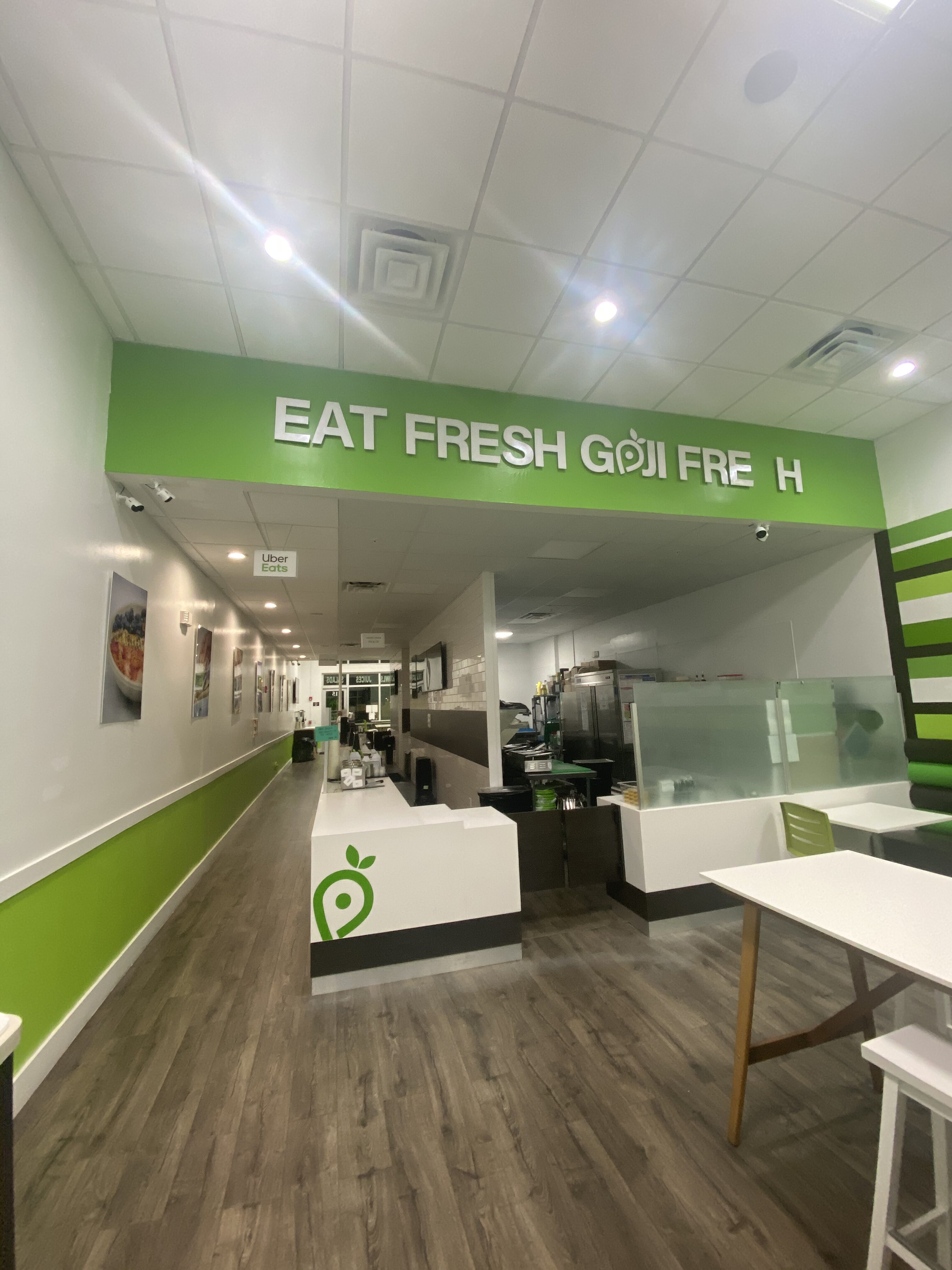 Inside a fast-casual restaurant with a bold white 'EAT FRESH' sign on a bright green wall above the service counter.