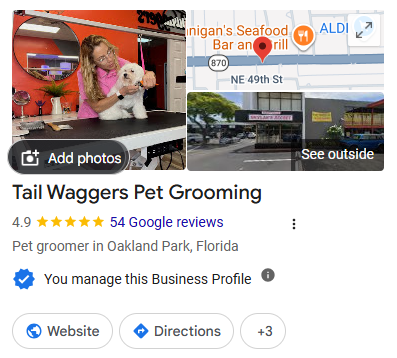 Tail Waggers Pet Grooming: groomer brushing a white dog inside the shop, with the storefront exterior shown.