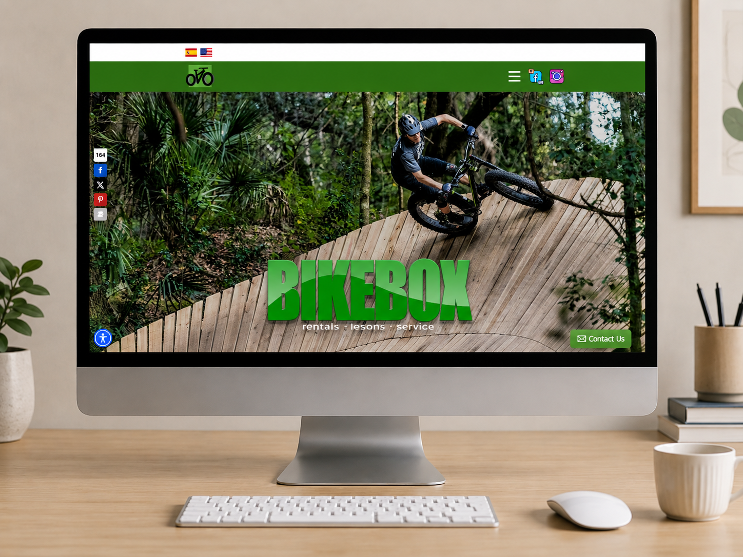 On-screen BikeBox homepage showing a cyclist on a wooden ramp in a forest, with a bold green BIKEBOX logo and 'rentals · lessons · service' text.