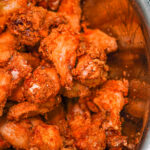 Close-up of crispy fried chicken pieces in a stainless steel bowl, showing orange-brown batter and crunchy coating.