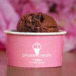 Close-up of a scoop of chocolate ice cream in a pink cup, with the 'phusecream' logo visible.