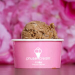 Ice cream scoop in a pink cup with a white logo, against a pink floral background.