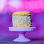 Macaron on a pink cake stand with a vibrant pink-purple bokeh background, close up view.