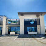 Front of a Laundry & Fold storefront with glass doors, stone columns, and a circular logo on a striped railing.