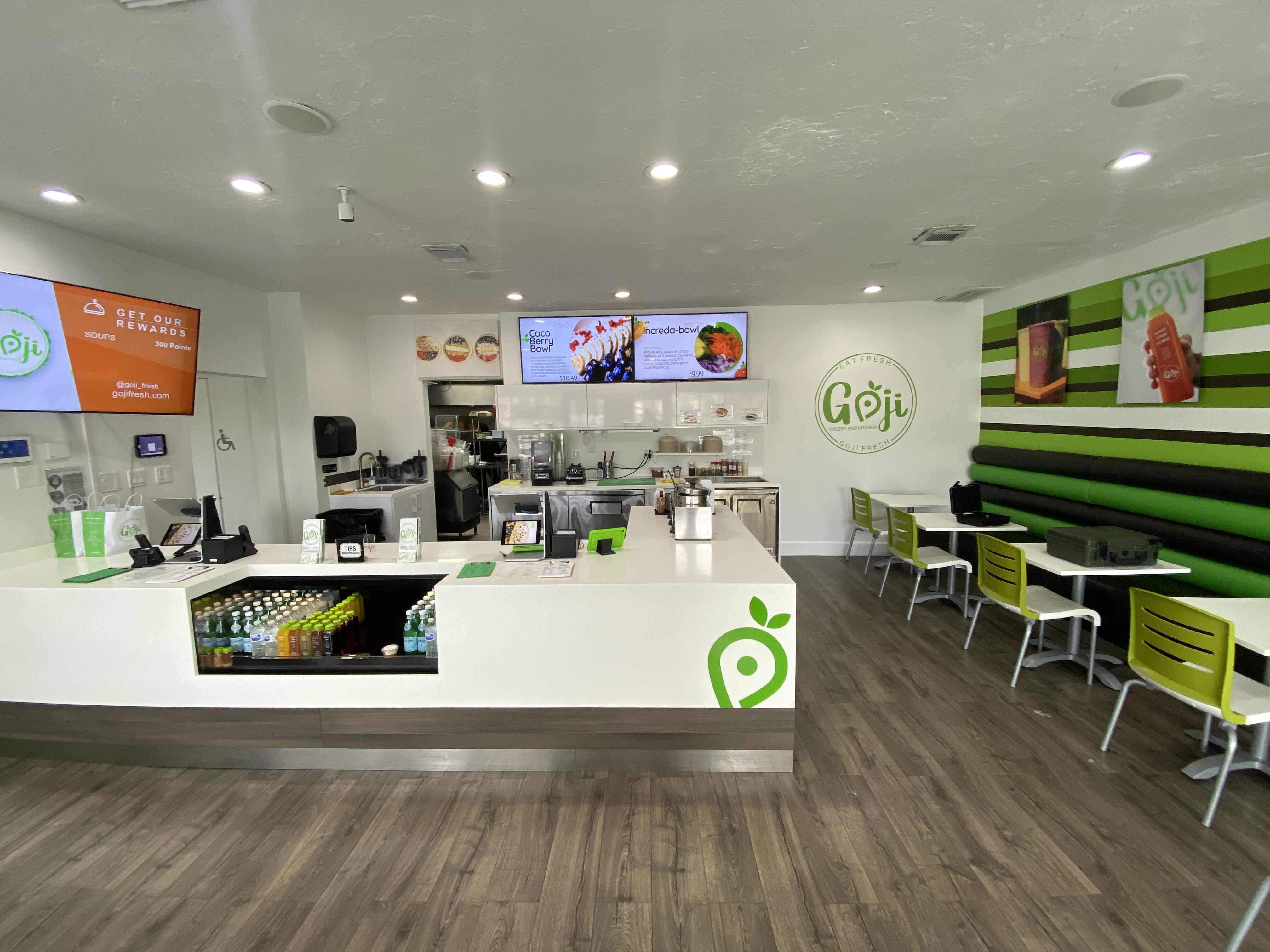 Bright smoothie shop interior with white counters, digital menu boards, and lime green accents.