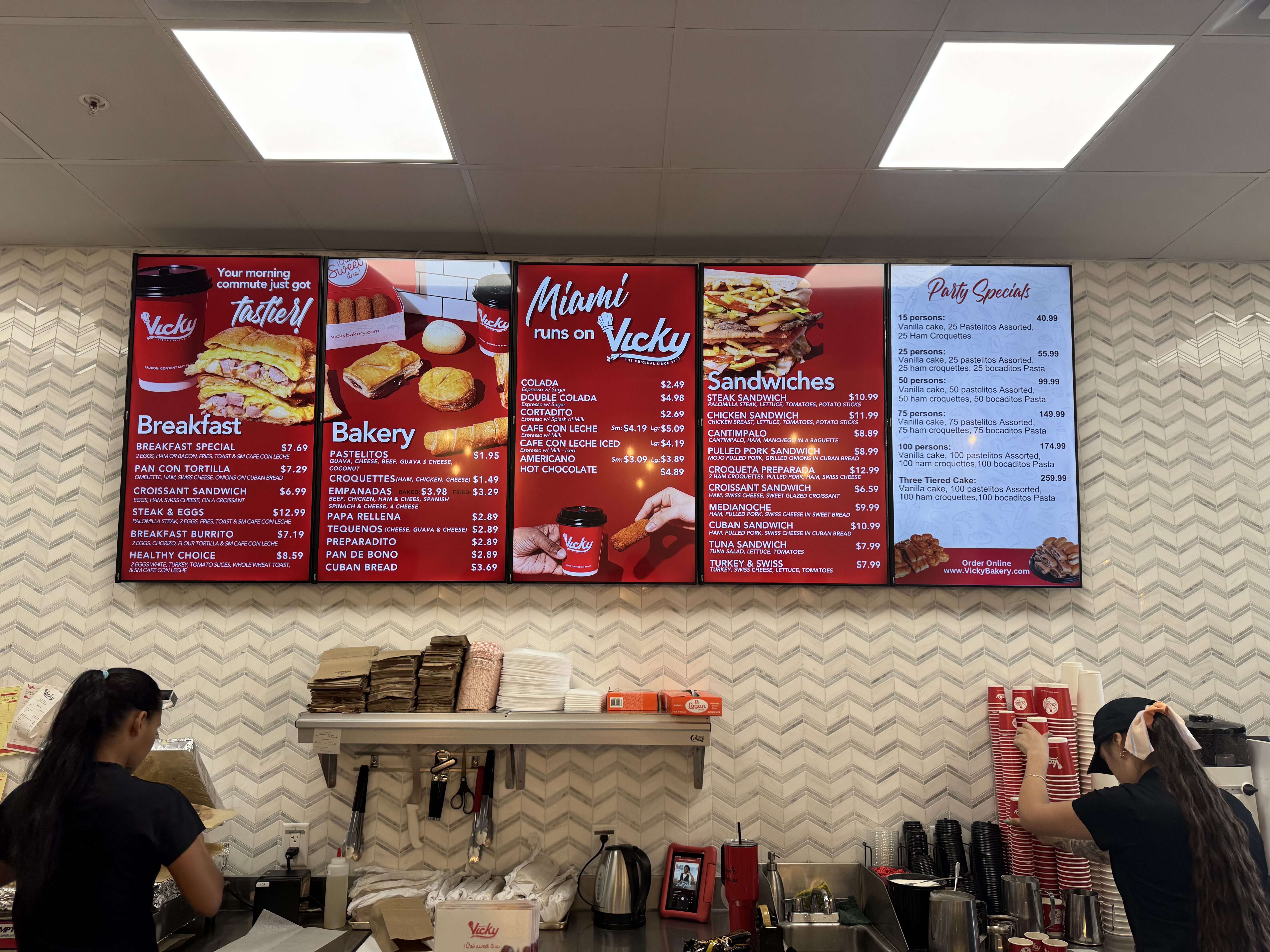 Bakery counter with large red menu boards showing breakfast, bakery items, and sandwiches at a fast-food shop.