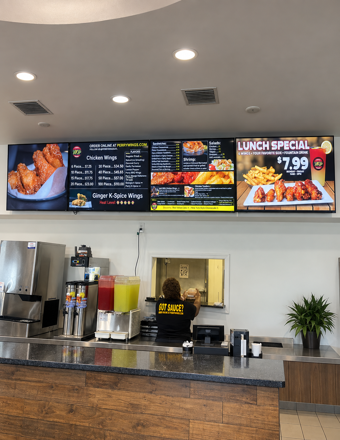 Inside a fast-food restaurant with digital menu boards above the counter and a worker taking an order at the service window.